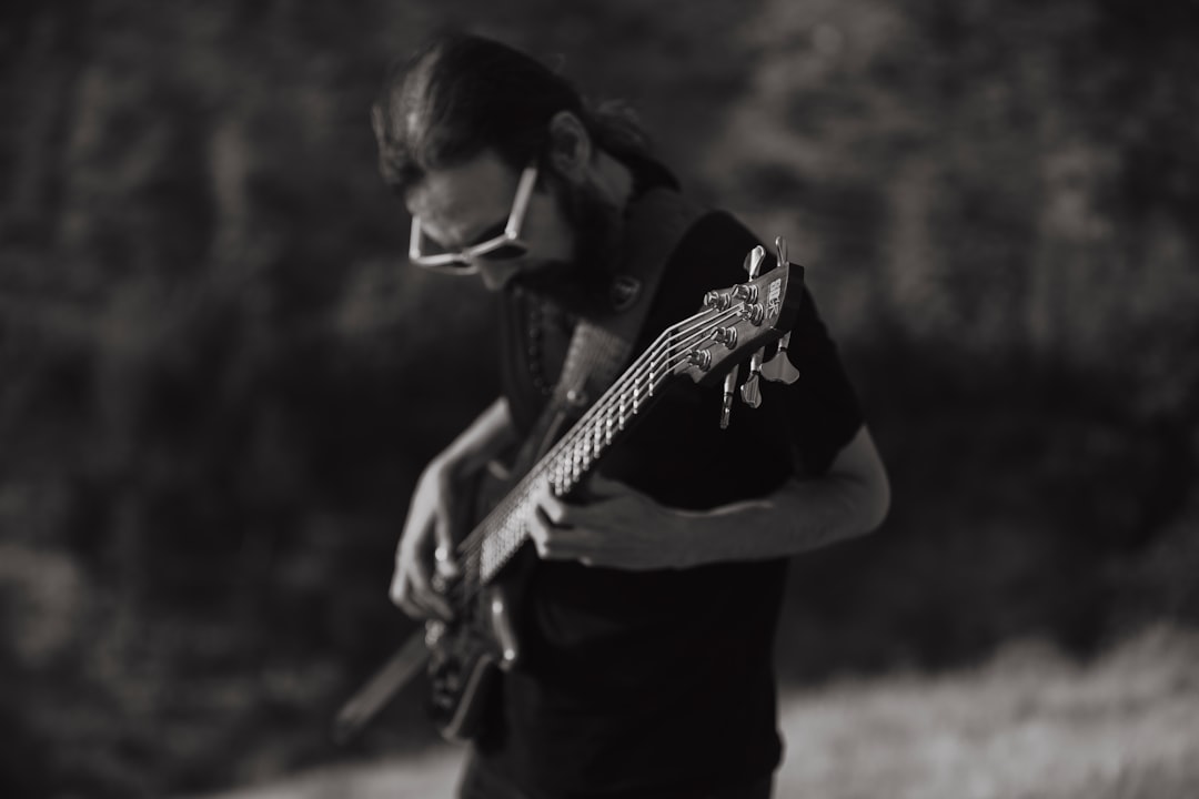 Man playing guitar outdoors in black and white