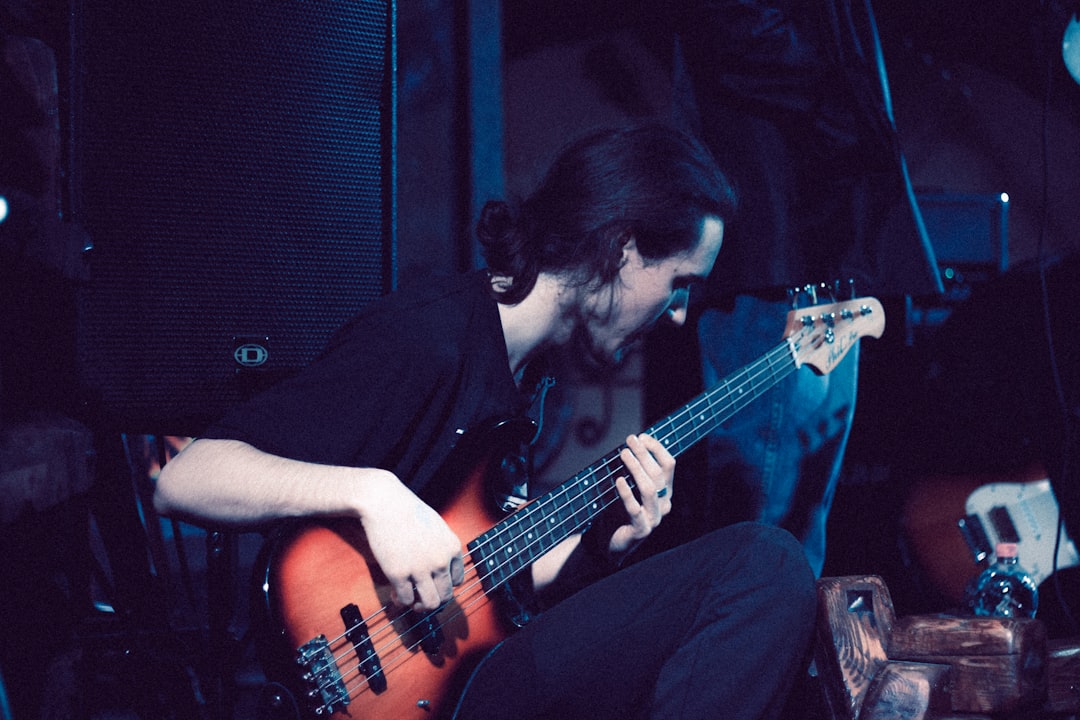 A man playing a bass guitar in a dark room